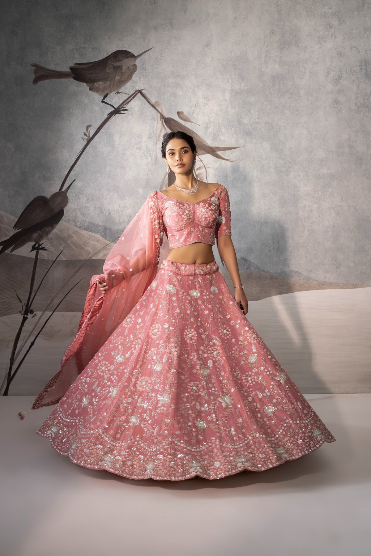 Woman in a pink traditional outfit with birds on a branch in the background