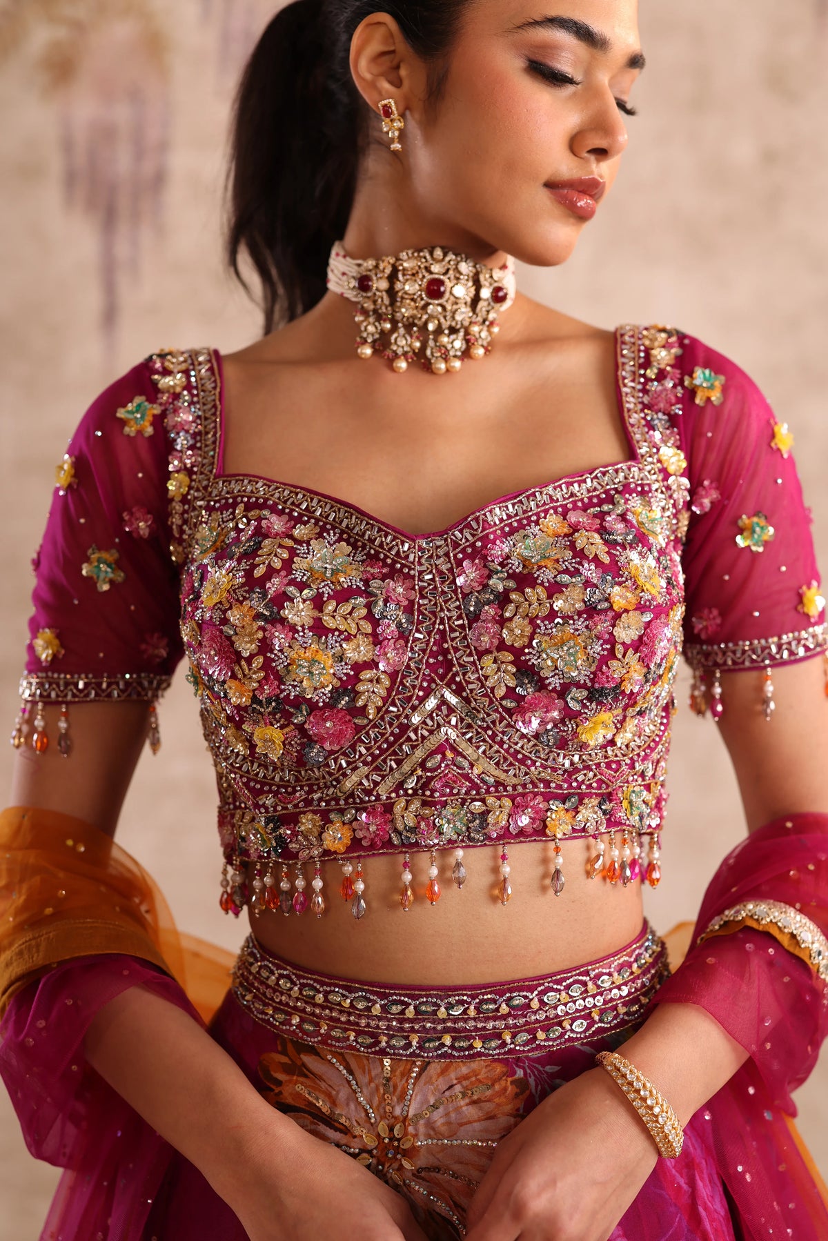 Woman wearing a traditional embroidered blouse with floral patterns and jewelry.