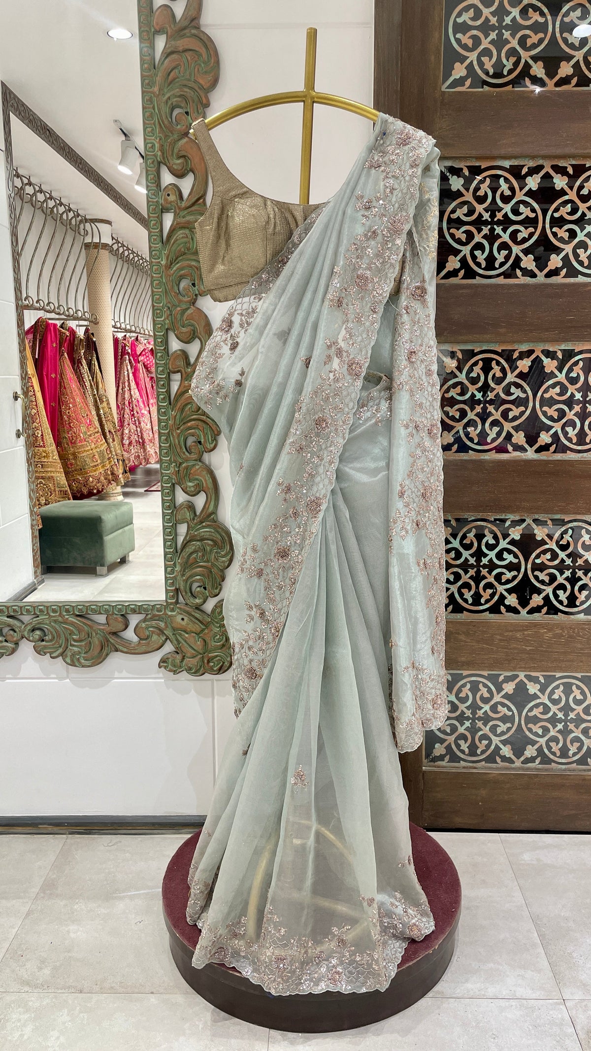 A blue tissue saree with zariwork displayed on a mannequin, with intricate embroidery and sequins detailing.