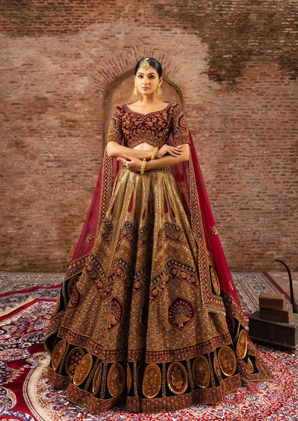 A woman wearing a Marwari-style bridal lehenga with Zardozi embroidery and peacock motifs, in a rich royal color tone, standing in a traditional setting.