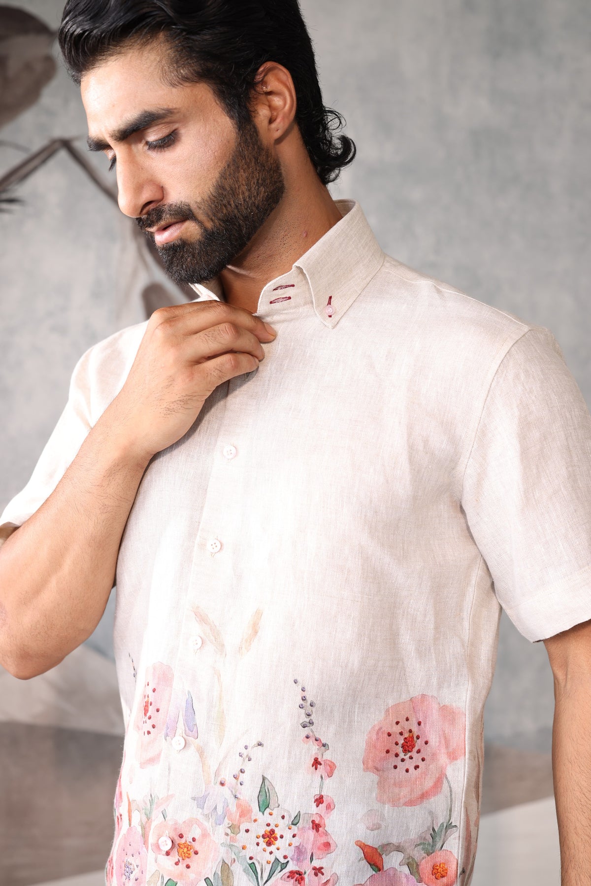 Man wearing a light-colored shirt with floral patterns against a neutral background