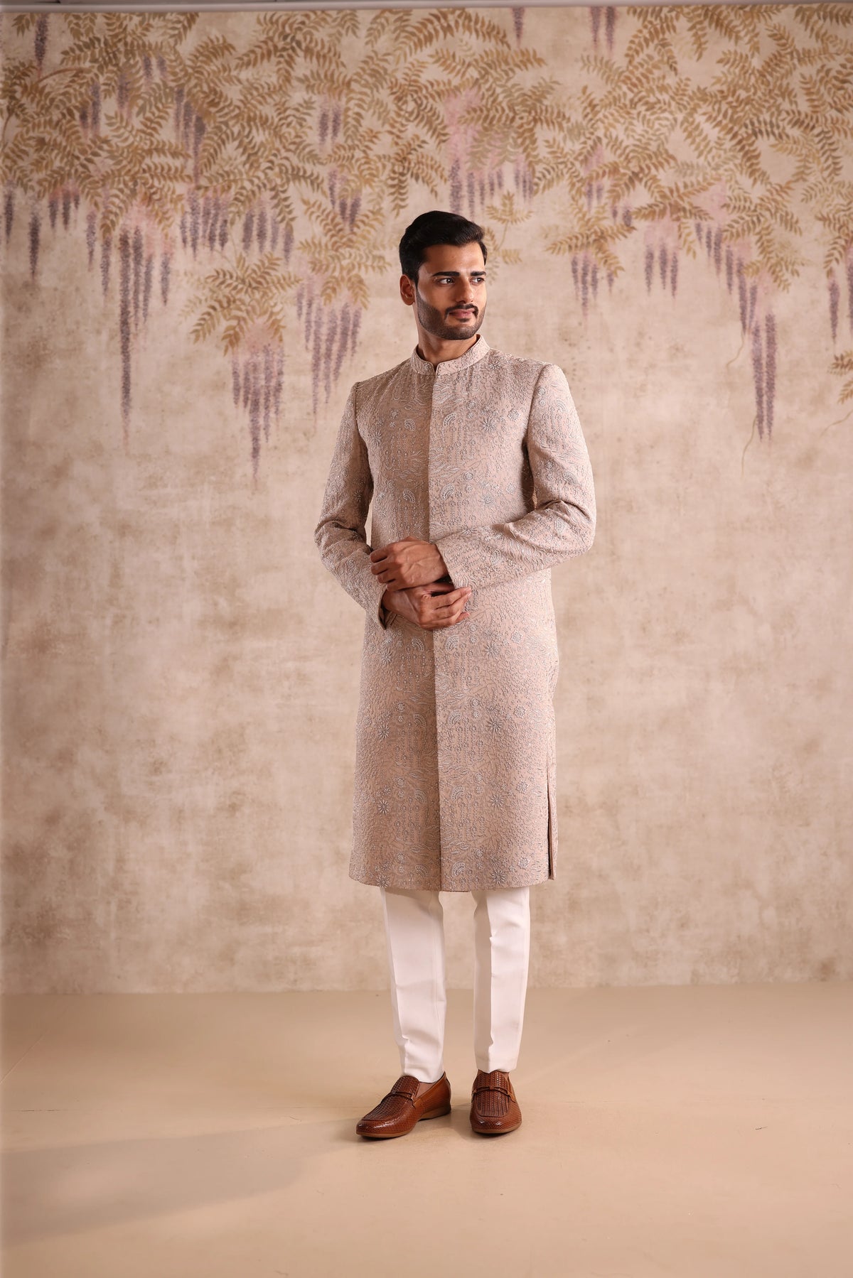 Man wearing a traditional kurta with a decorative wall in the background