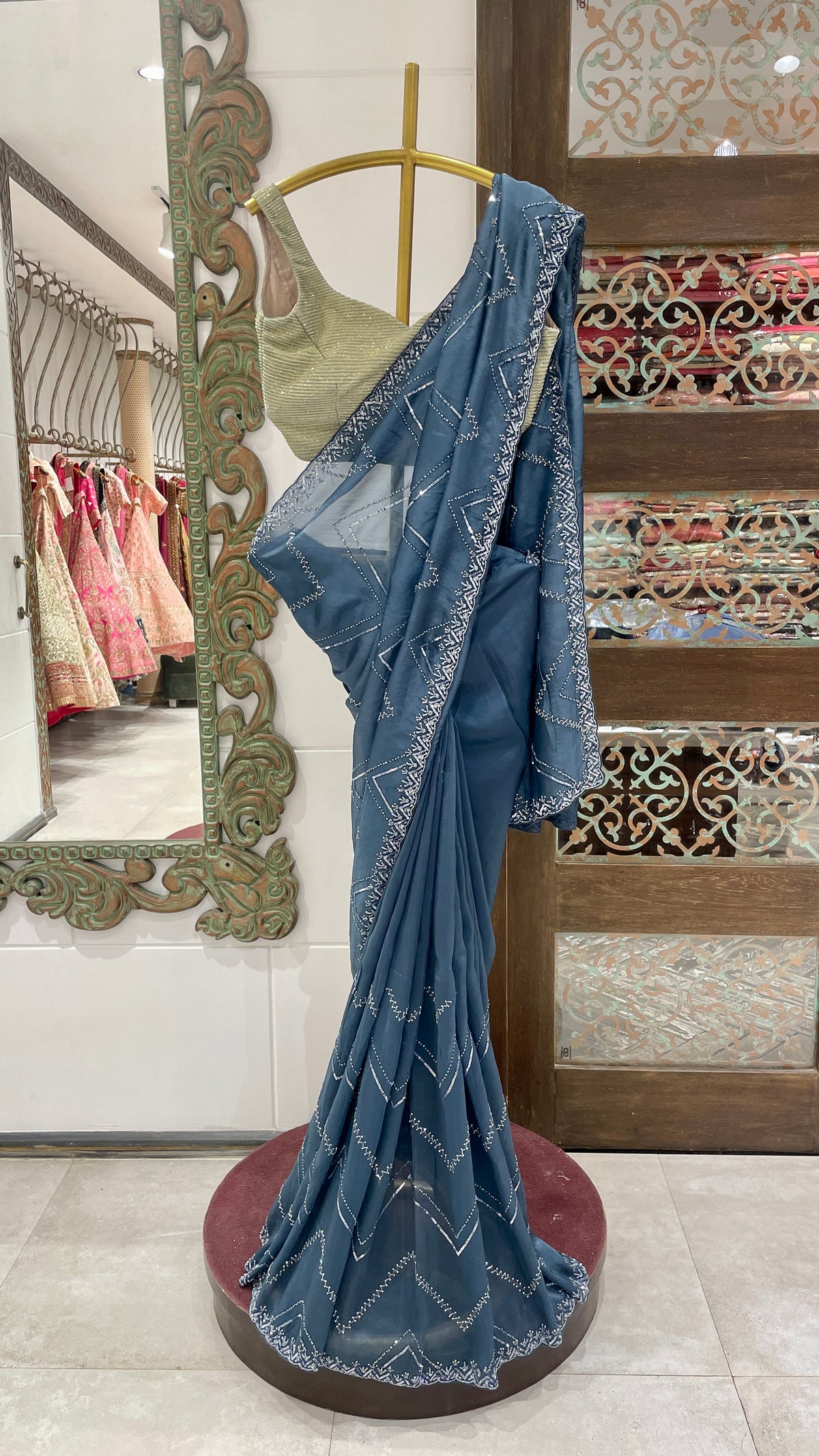 A blue organza saree with cutdana border displayed on a mannequin in a store.
